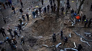 a crater created by a bomb that heavily damaged buildings and cars in Kyiv