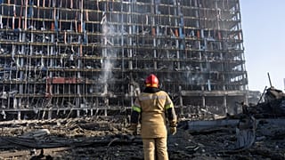 A firefighter looks at the destruction caused after shelling of a shopping center, in Kyiv, Ukraine, Monday, March 21, 2022.