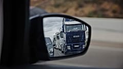 A long line of trucks driving slowly are reflected in a wing mirror of a car during a truckers strike in Torrejon de Ardoz, just outside of Madrid, Friday March 18, 2022