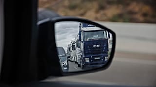 A long line of trucks driving slowly are reflected in a wing mirror of a car during a truckers strike in Torrejon de Ardoz, just outside of Madrid, Friday March 18, 2022