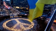 People stand around a giant peace sign with the message 'Stop Putin's Oil', put up by demonstrators ahead of an EU and NATO summit in Brussels, Tuesday, March 22, 2022.