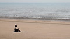 Two sunbathers sit and watch the sea on the sandy beach at Camber Sands, England.