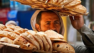 بائع يحمل صينية الخبز "البلدي" المصري التقليدي، بحي القاهرة القديمة في القاهرة، مصر، الثلاثاء 22 مارس 2022