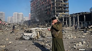 A priest prays by the ruins of a destroyed shopping center after shelling, in Kyiv, Ukraine, Monday, March 21, 2022.
