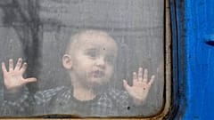 Un enfant regarde depuis un wagon de train, attendant de partir vers l'ouest de l'Ukraine à la gare de Kramatorsk, dans l'est de l'Ukraine, dimanche 27 février 2022.