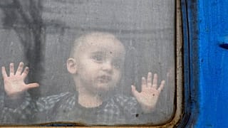 Un enfant regarde depuis un wagon de train, attendant de partir vers l'ouest de l'Ukraine à la gare de Kramatorsk, dans l'est de l'Ukraine, dimanche 27 février 2022.