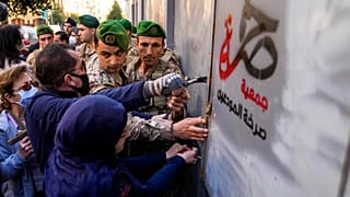 جنود لبنانيون يمنعون المودعين اللبنانيين من اختراق بوابة مصرفية محصنة أثناء محاولتهم اقتحام أحد البنوك في بيروت، لبنان،  18 شباط 2022.