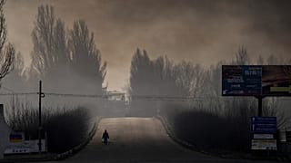 رجل يحمل أكياساً فيها مواد غذائية فيما الدخان الكثيف ينتشر من مستودع دمره القصف الروسي بالقرب من كييف، أوكرانيا، 24 مارس 2022
