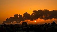 Um avião comercial passa por cima do fumo causado pelo incêndio numa refinaria