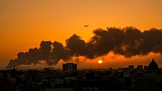 Um avião comercial passa por cima do fumo causado pelo incêndio numa refinaria