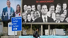 A man walks past election billboards in Msida on 24 March 2022