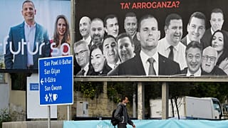 A man walks past election billboards in Msida on 24 March 2022