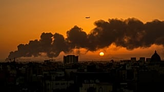 A passenger airplane flies over a smouldering fire at an Aramco oil depot after a Yemen Houthi rebel attack as the sun rises in Jiddah, 26 January 2022