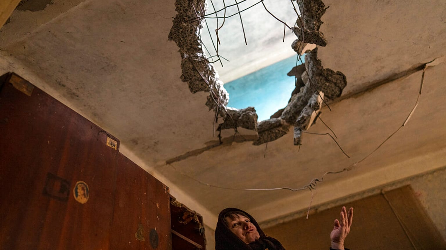 Halyna Falko talks to reporters while looking at the destruction caused after a Russian attack inside her house.