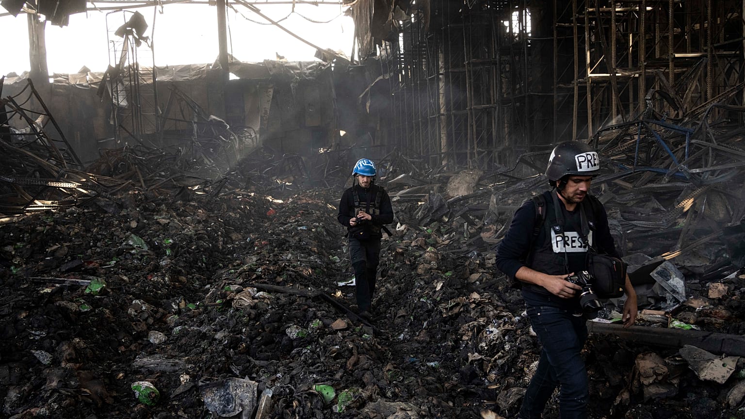 Periodistas caminan por el interior de un almacén destruido para almacenar alimentos, tras un ataque de Rusia hace doce días en Brovary, en las afueras de Kiev, el 29 de marzo