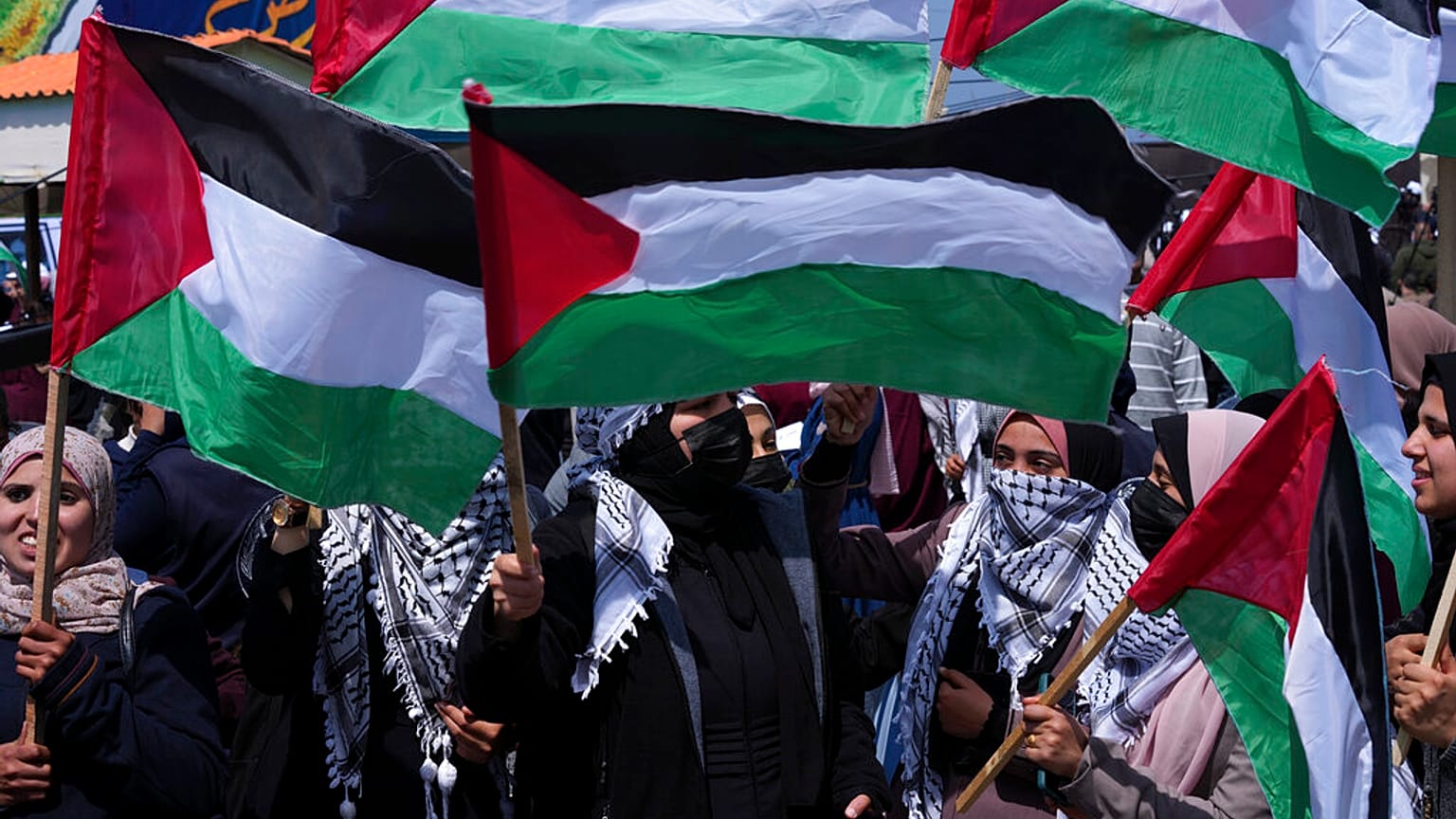 نساء فلسطينيات يلوحن بأعلامهن الوطنية خلال مسيرة لإحياء الذكرى 46 ليوم الأرض، في ميناء الصيادين في مدينة غزة، الأربعاء 30 مارس 2022