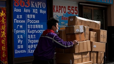 A courier worker moves goods past a shipping company for the countries including Russia and Ukraine, at a trading center also known as Russia Market in Beijing.