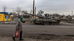 Idős nő egy megsemmisült orosz páncélozott harci jármű roncsa előtt Trosztyanecben