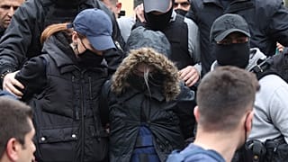 The woman wore a hood and a protective vest as she was escorted out of court.