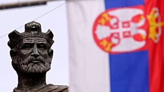 Сербский флаг на фоне памятника Лазарю Хребеляновичу в Косовска-Митровице