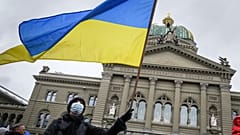 Ein Mann schwenkt bei der Kundgebung gegen den Krieg eine ukrainische Fahne vor dem schweizer Parlamentsgebäude.
