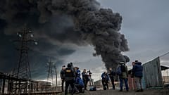Journalists and residents stand as smoke rises after an attack by Russian army in Odessa, on April 3, 2022.