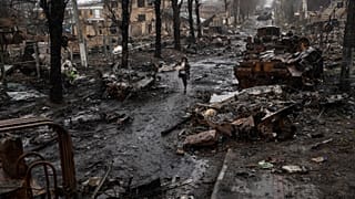 A woman walks amid destroyed Russian tanks in Bucha, in the outskirts of Kyiv, Ukraine, Sunday, April 3, 2022.