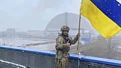 Egy katona az ukrán lobogóval a csernobili erőmű szarkofágja előtt