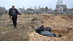 Un homme près d'une fosse commune à Boutcha (Ukraine), le 3 avril 2022