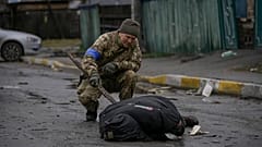 Un soldado ucraniano examina un cadáver en una calle de Bucha.