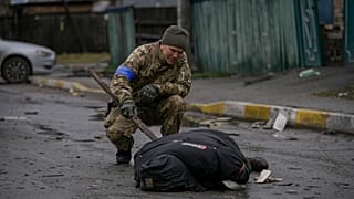 Un soldado ucraniano examina un cadáver en una calle de Bucha.