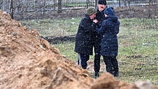 Люди у братской могилы в Буче к северо-западу от Киева / 3 апреля 2022 года