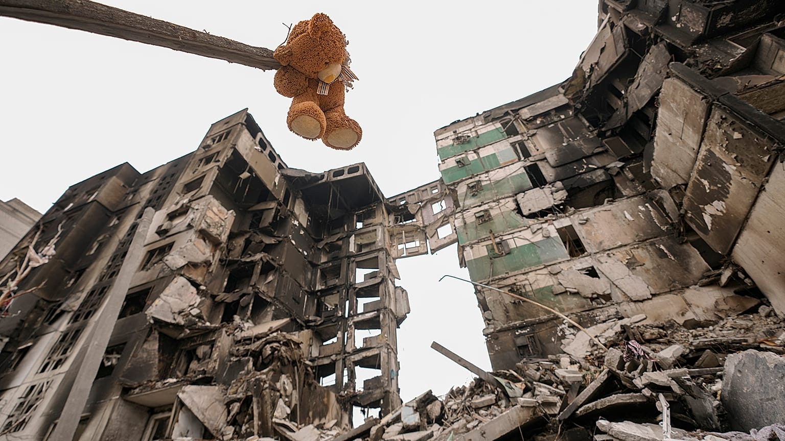 A teddybear hangs from a branch of a torn tree outside an apartment building in Borodyanka