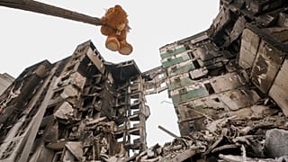 A teddybear hangs from a branch of a torn tree outside an apartment building in Borodyanka