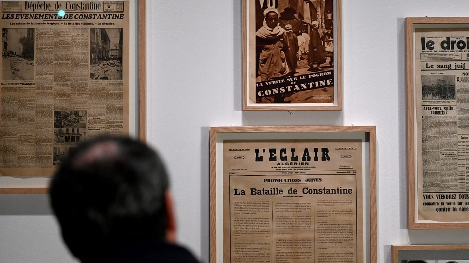 زائر يشاهد جرائد حول أعمال الشغب المناهضة لليهود في قسنطينة عام 1934 خلال معرض "اليهود والمسلمون من فرنسا الاستعمارية إلى الوقت الحاضر"، في متحف تاريخ الهجرة بباريس