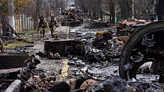 Des soldats ukrainiens marchent au milieu de chars russes détruits à Boutcha