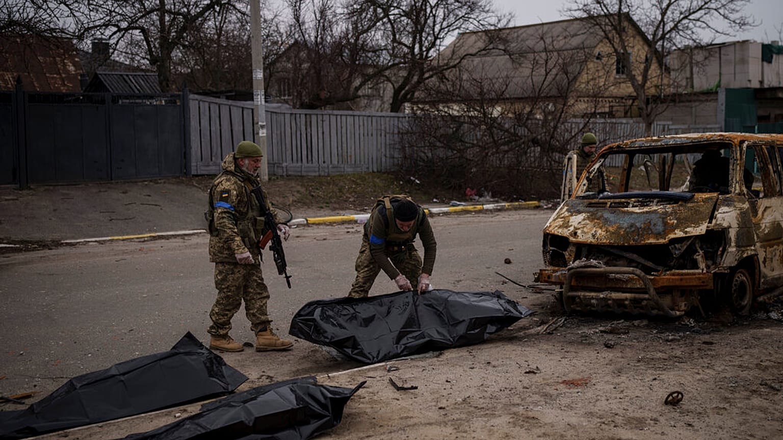 Des soldats ukrainiens récupèrent les restes de quatre civils tués à l'intérieur d'un véhicule calciné à Bucha, en Ukraine, mardi 5 avril 2022.
