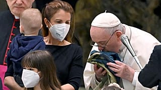Pope Francis kisses a Ukrainian flag