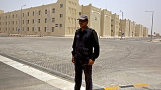 صورة أرشيفية تعود لعام 2015، فيها يقف حارس أمن أمام منشأة جديدة تديرها الحكومة لاستيعاب حوالي 70 ألف عامل في الدوحة.