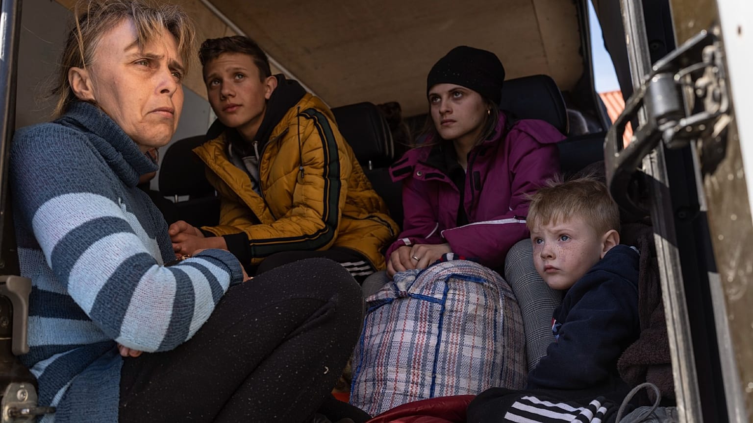 From left to right, Oksana Gavrielutca 41, sits at the back of a bus with her children Oleg 18, Diana 17 and Vlad 5 after they flee from Snigiriovka village, in Mikolaiv distr