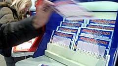  A customer picks up a Lotto ticket in a Paris shop in 2006. 
