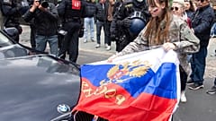 Участница автопробега в поддержку РФ снимает российский флаг по просьбе полицейских, Франкфурт, Германия, 10 апреля 2022 г.