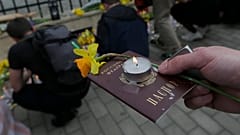 A demonstrator holds a Russian passport with a candle and a flower during an anti-war action in front of Ukrainian Embassy in Tbilisi, Georgia.