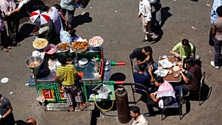 بائع متجول مصري يقف بجانب عربته يقدم وجبة الفول التقليدية في أحد شوارع القاهرة، مصر، الجمعة 20 أبريل 2012