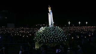 The statue of Our Lady of Fatima is carried past worshippers holding candles in a procession at the Catholic shrine in Fatima, Portugal, Wednesday, May 12, 2021.