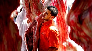 رجل مصري يحمل لحمًا استعدادًا لعطلة عيد الأضحى المبارك في سوق جزارين في القاهرة، مصر، الخميس 2 أكتوبر / تشرين الأول 2014.