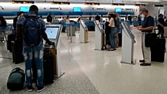 Travelers use the self-service kiosk to check in and pay for luggage at the American Airlines terminal, in Miami.