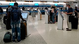 Travelers use the self-service kiosk to check in and pay for luggage at the American Airlines terminal, in Miami.