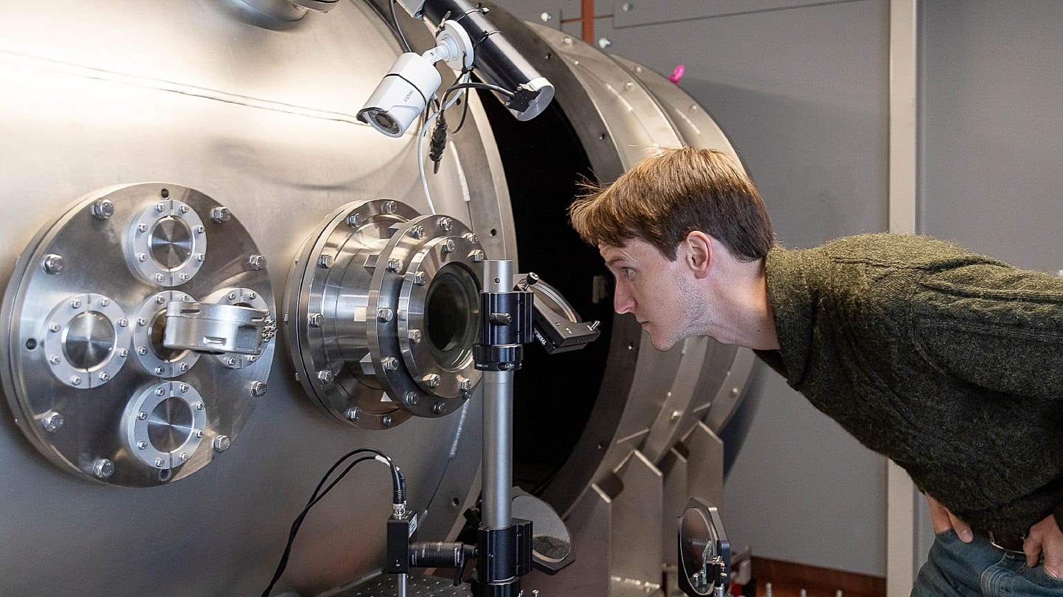 Image shows CEO and Co-founder of First Light Fusion, Dr. Nick Hawker inspecting machinery at his factory that aim to cheaply create green energy via nuclear fusion.