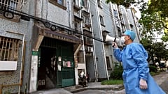 Волонтёр общается с жителями при помощи мегафона. Шанхай, 12 апреля 2022 года